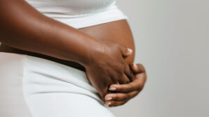 close-up of a black woman's hands gently embracing the stretch marks on her belly, pregnant woman, body positivity