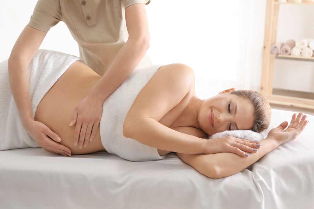 Young beautiful pregnant woman having massage in spa salon