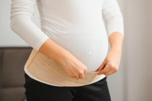 Pregnant woman in back brace to support acupuncture for back pain in pregnancy